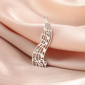 Détail de pendentif note de musique argenté sur soie rose, accessoire bijoux en acier inox