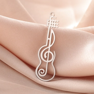 Detailed view of silver guitar and musical note pendant on elegant pink silk background