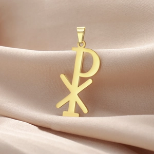Macro detail of golden Chi-Rho religious pendant on elegant pink silk background