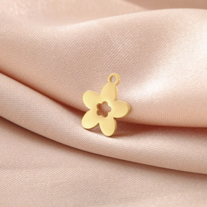 Vue macro d'un pendentif fleur en acier doré posé sur un tissu en soie violette