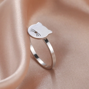 Cute hollow cat head ring in polished silver finish on soft silk background texture