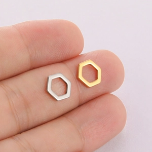 Polished gold and silver hexagonal hollow pendants shown held for scale on purple background