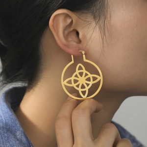 Minimalist gold hollow Celtic knot round earrings for women on female model ear