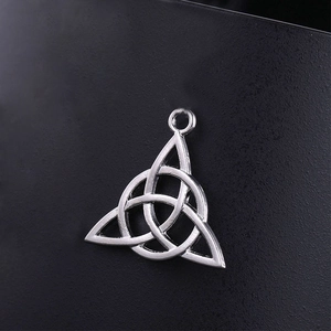 Colgante Triquetra nudo celtico de plata vintage sobre fondo negro con textura
