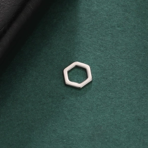 Macro view of mirror polished stainless steel hexagon pendant on a dark textured surface