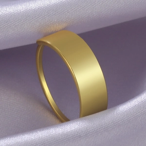Dettaglio anello piatto oro minimalista su sfondo di seta viola con texture morbida