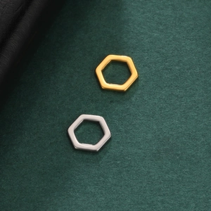 Polished gold and silver hexagonal stainless steel pendants on a dark green background