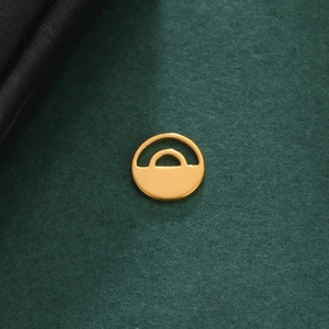 Nahaufnahme des goldfarbenen 10x10mm runden Anhängers mit hohlraumstruktur auf grünem Hintergrund