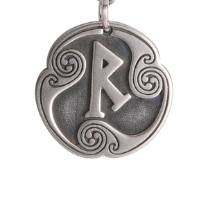 Detalle de un colgante de plata antigua con la letra R grabada y motivos celtas