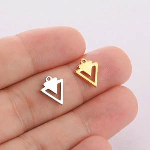 Macro shot of gold and silver geometric triangle pendants held on a finger for scale