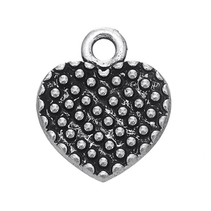 Détail d'un pendentif cœur vintage en argent avec texture à pois noirs et argentés