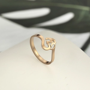 Detail view of rose gold stainless steel Om ring with Hindu symbol on white surface