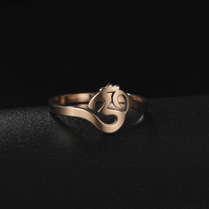 Macro shot of rose gold stainless steel Om symbol ring on a textured black display