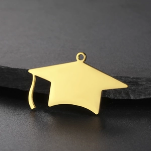 Polished 18K gold graduation cap pendant with high-gloss finish on natural stone background