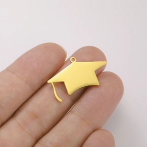 Detailed close-up of a golden mortarboard graduation cap pendant held on a finger