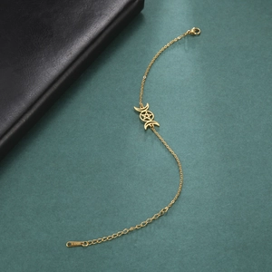 Detalle de la tobillera de acero inoxidable dorado con colgante de triple luna y pentagrama