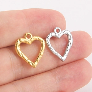Vue macro de pendentifs en forme de cœur évidé en or et argent avec textures gravées