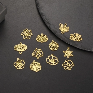 Set aus goldenen, hohlen Blumenanhängern auf schwarzem, strukturiertem Hintergrund