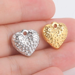 Détail de pendentifs en forme de cœur martelé en or et argent sur la main