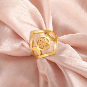 Detailed macro of gold pentagram and crescent moon ring on pink silk fabric background