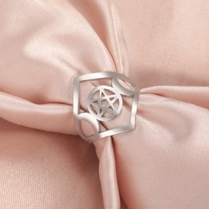 Macro shot of silver stainless steel pentagram ring on elegant pink silk fabric background