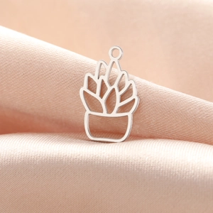 Detailed close-up of a silver stainless steel cactus pendant on silk fabric background
