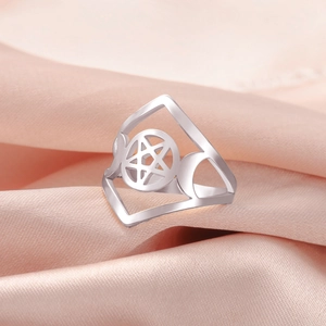 Macro shot of stainless steel pentagram and triple moon ring on pink satin fabric