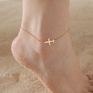 Detail der 18K Gold-Edelstahl-Ankerkette mit Flugzeuganhänger auf Sandstrand