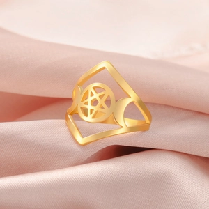 Macro shot of gold stainless steel pentagram ring with crescent moons on pink silk fabric