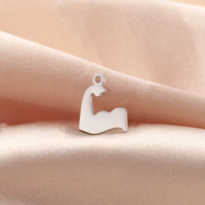Macro shot of mirror-polished stainless steel muscular arm pendant on pink silk