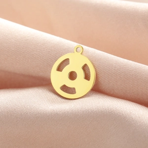 Detailed close-up of a golden dumbbell pendant on soft pink silk background