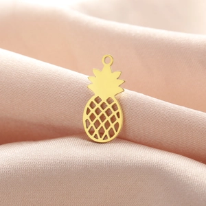 Detailed close-up of a gold pineapple pendant with hollow mesh design on pink velvet