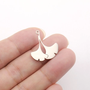 Polished stainless steel ginkgo leaf pendants on fingertips showing natural size and detail