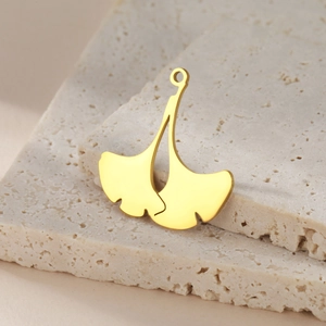 Polished gold double ginkgo leaf stainless steel pendant on a natural stone base