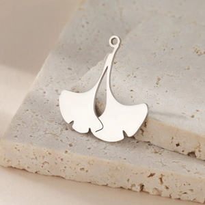 Polished stainless steel ginkgo leaf pendants for DIY jewelry making on stone background