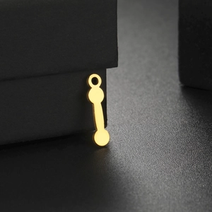 Macro detail of golden dumbbell pendant with smooth finish and top ring hanging accessory