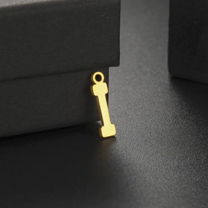 Macro view of a polished gold letter I pendant featuring a mirror finish on a jewelry box