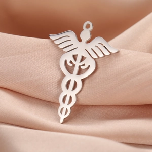 Detalle del colgante médico caduceo de acero inoxidable sobre fondo de seda rosa