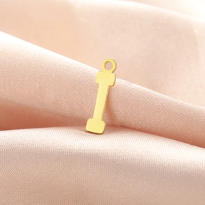 Detailed macro view of a polished gold dumbbell pendant charm for DIY jewelry making