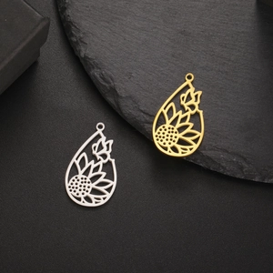 Polished gold and silver sunflower butterfly teardrop charms on a stone pedestal
