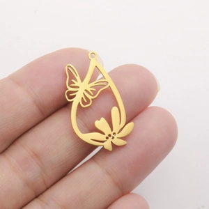 Macro view of gold stainless steel teardrop pendant with butterfly and flower cutout