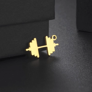 Macro detail of golden dumbbell pendant for fitness necklace on black matte background