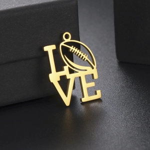 Dettaglio del ciondolo LOVE dorato con design football su scatola regalo nera