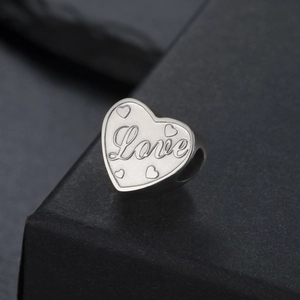 Détail macro du pendentif cœur argenté avec gravure Love et trou latéral pour bijoux DIY