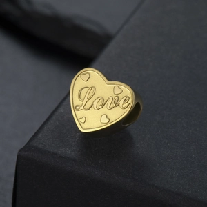 Vue macro d'une breloque cœur dorée avec gaufrage Love pour bracelets DIY