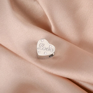 Vue macro d'un pendentif cœur en acier inoxydable avec gravure Love sur soie champagne