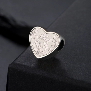 Gros plan d'un pendentif cœur en argent avec gravure Big Sister et motifs floraux