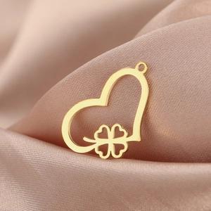 Golden heart clover necklace pendant in stainless steel on silk fabric background