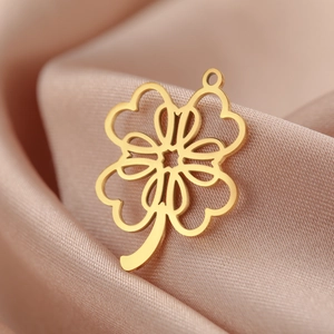 Makroaufnahme von goldenem Kleeblatt-Anhänger auf rosa Seide mit feinen Details