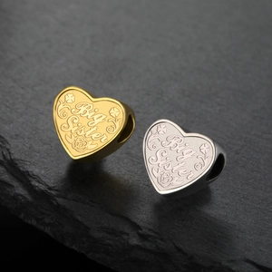 Vue macro de pendentifs en forme de cœur or et argent gravés Big Sister et motifs floraux